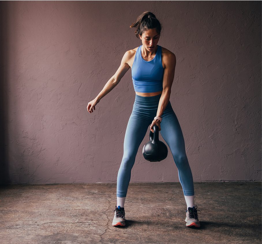 Woman exercising with a kettlebell indoors.